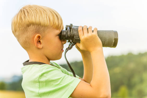 istock Young boy looking through binoculars, outdoors 1082955148