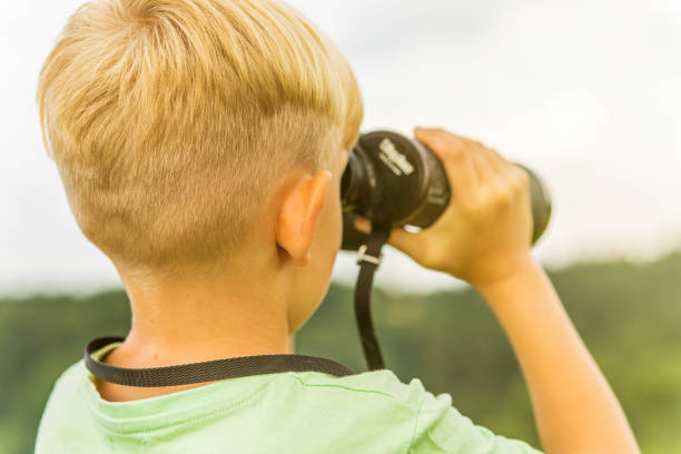 istock Young boy looking through binoculars, outdoors 1082955192