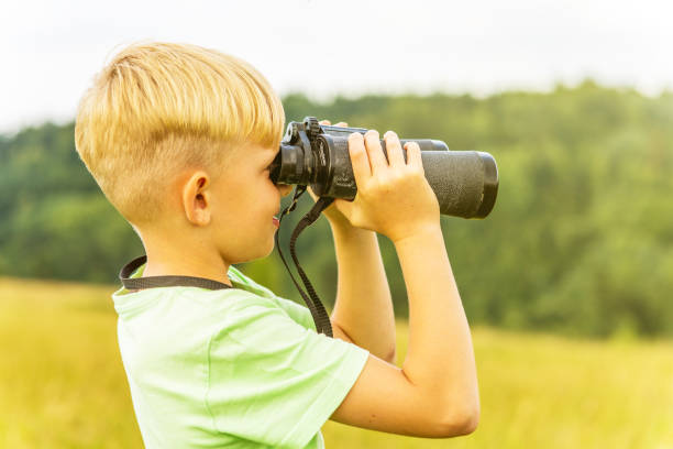 istock Young boy looking through binoculars, outdoors 1082955230