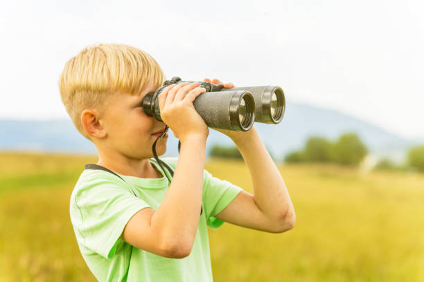 istock Young boy looking through binoculars, outdoors 1082955232