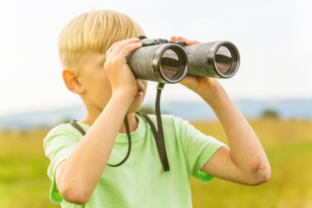 istock Young boy looking through binoculars, outdoors 1082955244