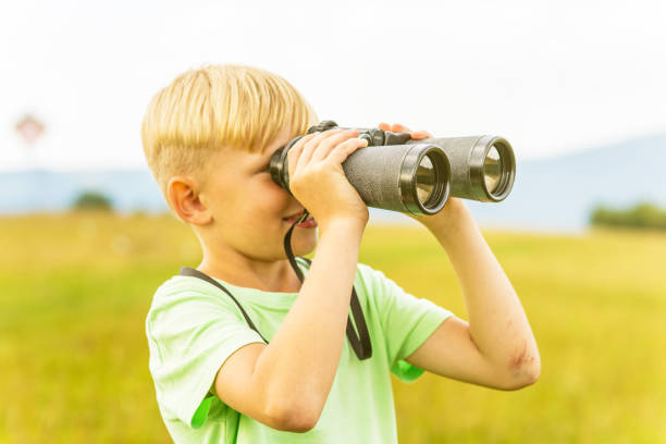 istock Young boy looking through binoculars, outdoors 1082955258