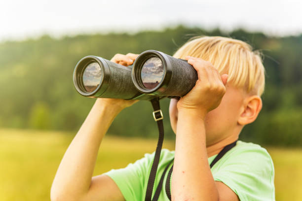 istock Young boy looking through binoculars, outdoors 1082955318