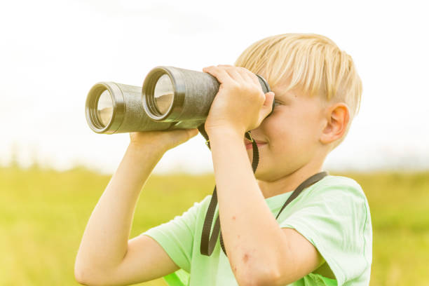 istock Young boy looking through binoculars, outdoors 1082955320