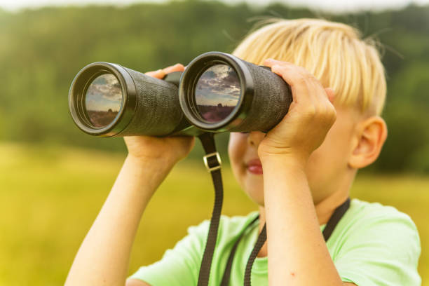 istock Young boy looking through binoculars, outdoors 1082955350
