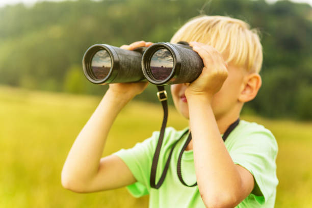istock Young boy looking through binoculars, outdoors 1082955424