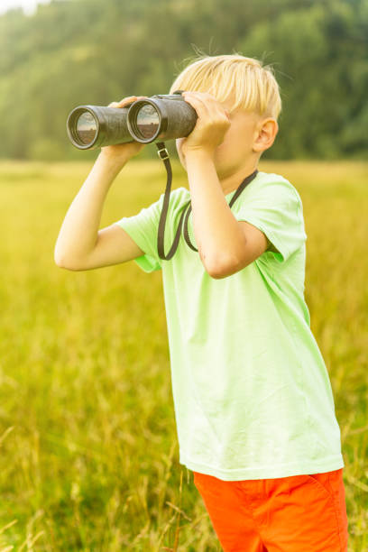 istock Young boy looking through binoculars, outdoors 1082955428
