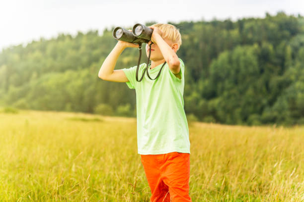 istock Young boy looking through binoculars, outdoors 1082955806