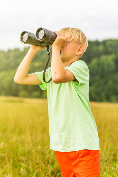 istock Young boy looking through binoculars, outdoors 1082955810