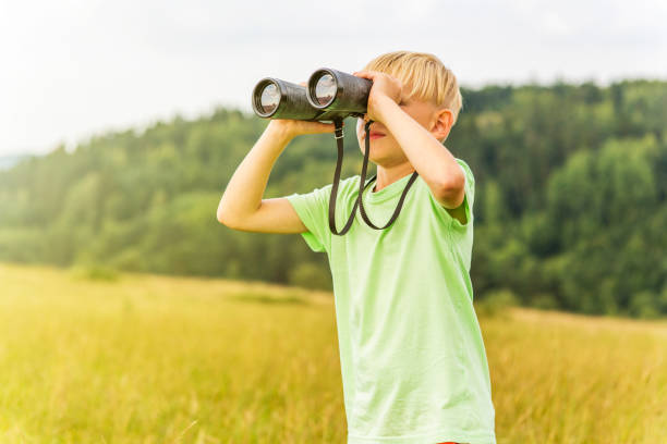 istock Young boy looking through binoculars, outdoors 1082955992