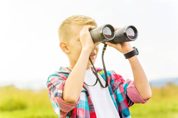 istock Young boy looking through binoculars, outdoors 1082956660