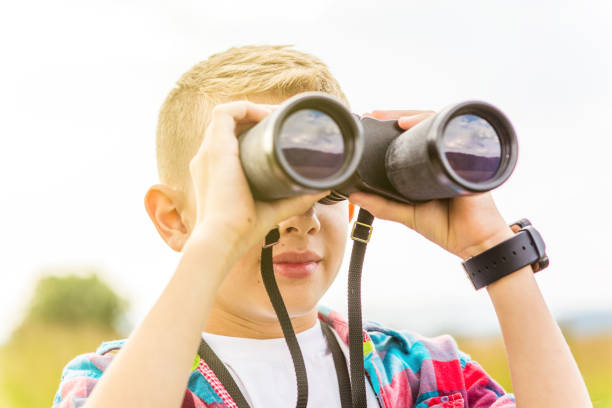 istock Young boy looking through binoculars, outdoors 1082956700