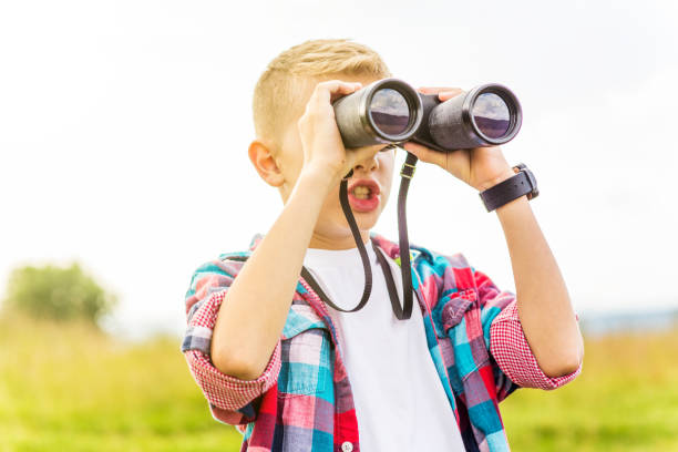 istock Young boy looking through binoculars, outdoors 1082956714