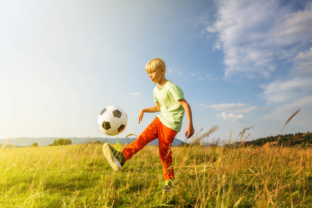 istock Boy playing football in a meadow, having fun 1082969130