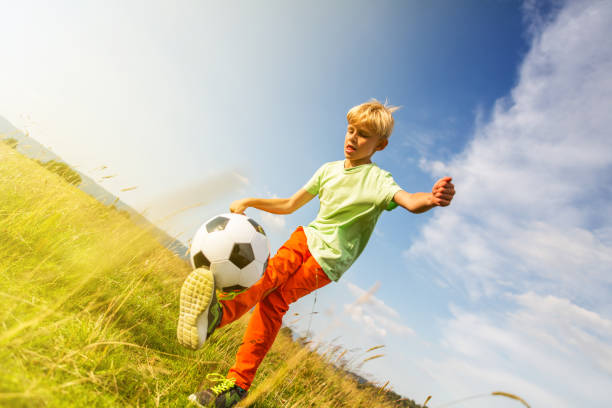 istock Boy playing football in a meadow, having fun 1082969164