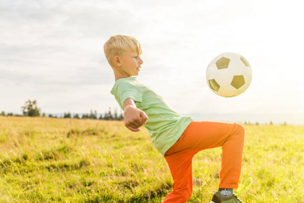 istock Boy playing football in a meadow, having fun 1082969876
