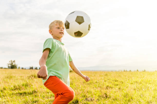 istock Boy playing football in a meadow, having fun 1082970270