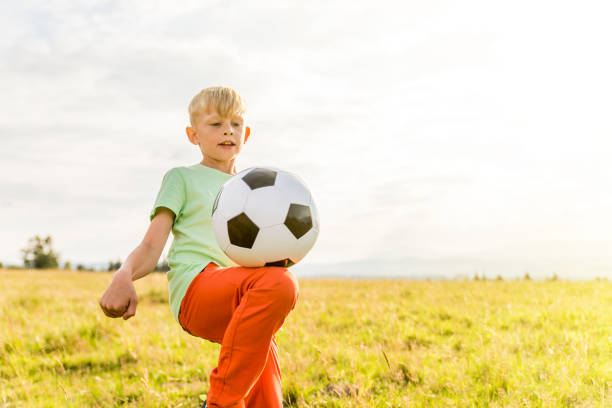 istock Boy playing football in a meadow, having fun 1082970548