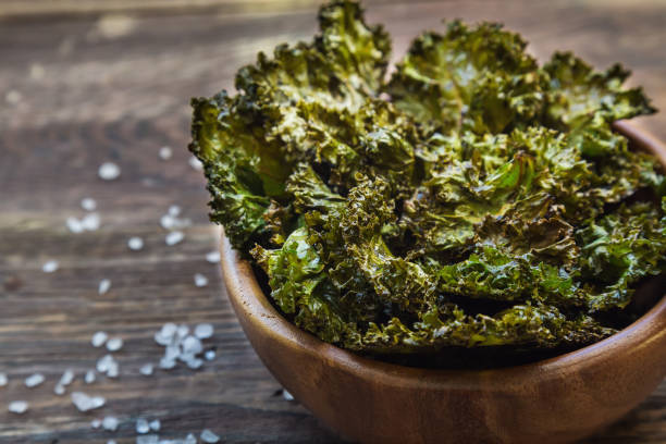 Homemade green kale chips baked with balsamic vinegar in bowl on rustic wooden background Healthy snack. Selective focus. kale photos stock pictures, royalty-free photos & images
