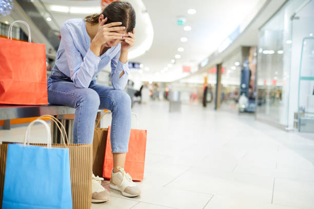 Exhausting shopping Tired shopper holding by head while sitting on bench among paperbags with purchases in the mall spree river photos stock pictures, royalty-free photos & images