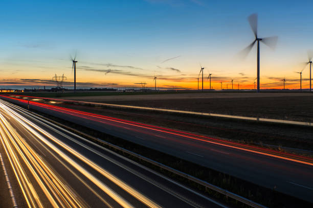 Heavy traffic on the highway at sunrise view of the A1 motorway at sunrise with a wind farm sunrise timelapse stock pictures, royalty-free photos & images