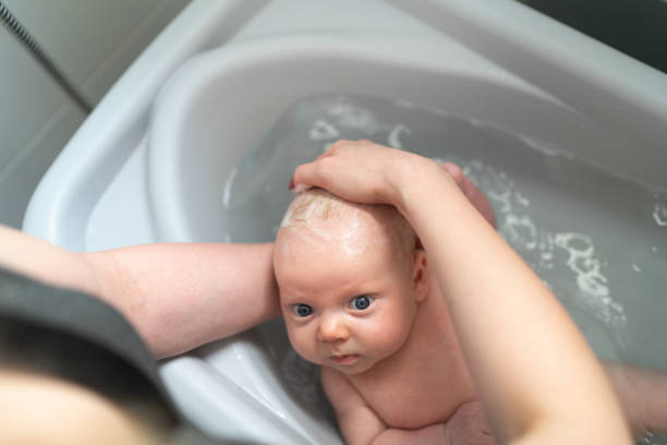 maman qui donne à son fils une douche à la maison - prendre un bain photos et images de collection