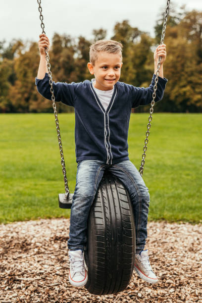 boy playing on tire swing - freedom tire swing tire swing imagens e fotografias de stock