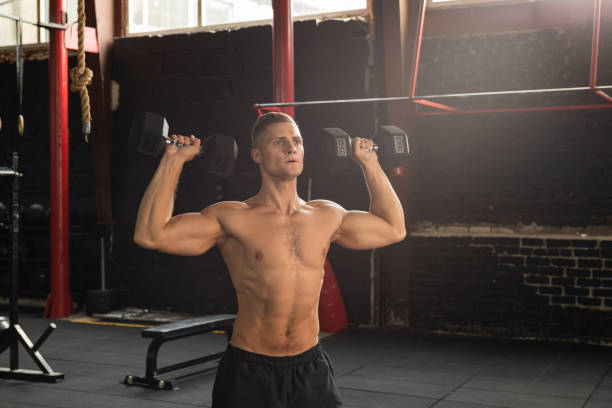 young handsome bodybuilder doing shoulder press - deltoid imagens e fotografias de stock