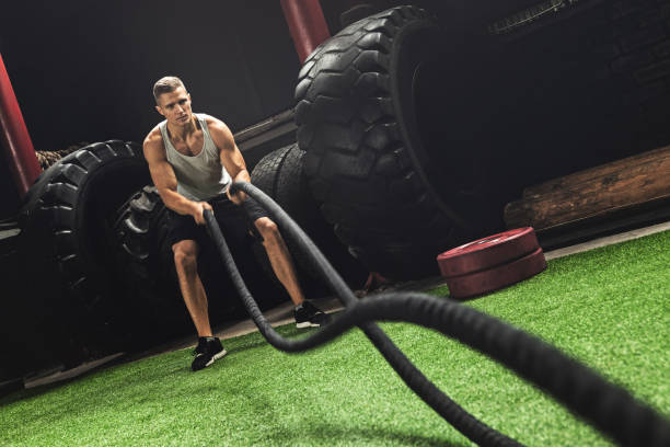 istock Man is making battle rope exercises during his cross training workout 1083007520
