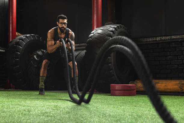 istock Man is making battle rope exercises during his cross training workout 1083007560