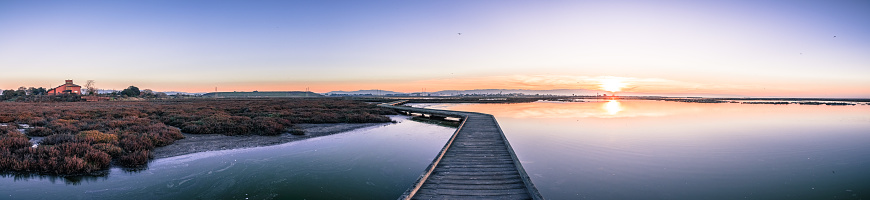 Wooden boardwalk through the tidal marshes of Alviso, Don Edwards San Francisco Bay National Wildlife Refuge, San Jose, California; sunset view