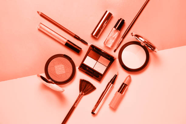 Coral colored Decorative cosmetic and nail polishes set on coral background. Minimalism cosmetics style. Top view, flat lay. Creative fashion beauty concept of color of the year 2019.