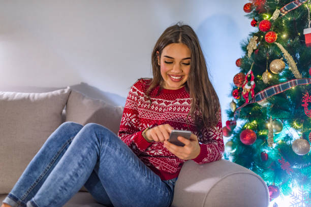 istock Woman with smartphone in front of Christmas tree 1083032176