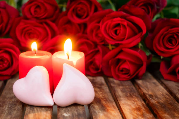 istock Two burning candles with fresh roses 1083059402
