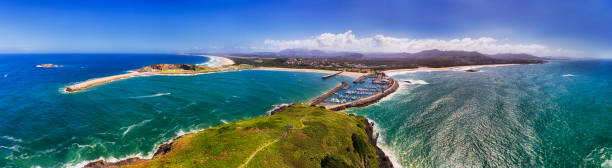 D Coffs Harbour Island 2 shore pan Aerial panorama of COffs Harbour town and coast from Muffonbird island in Pacific ocean facing sandy beach and harbour marina behind wave breaking wall. coffs harbour stock pictures, royalty-free photos & images