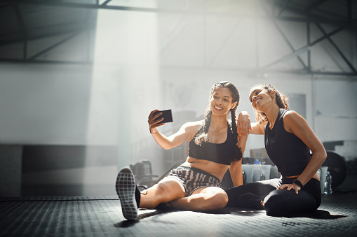 Shot of two women taking a selfie while sitting in the gym