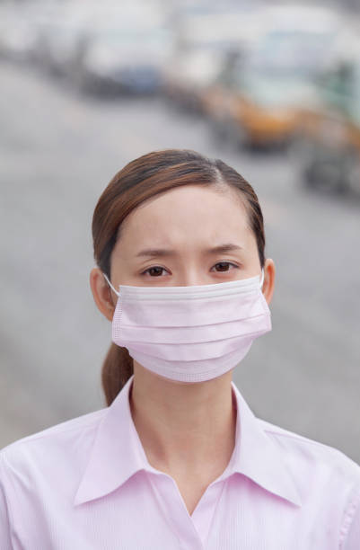 mulher chinesa usando máscara de rosto por causa da poluição do ar na cidade - smog china beijing pollution - fotografias e filmes do acervo