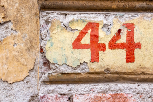 istock Number 44 in red peeling paint on an old brick building wall with cracked plaster 1083080260