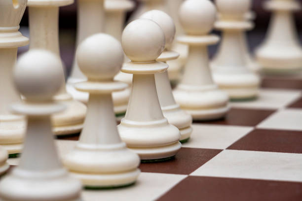 istock White pawn on a chess board among blurred white pawns in the row 1083080284