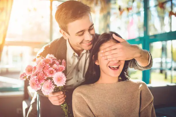 Photo of The happy man make a surprise with flowers for a girlfriend in the restaurant