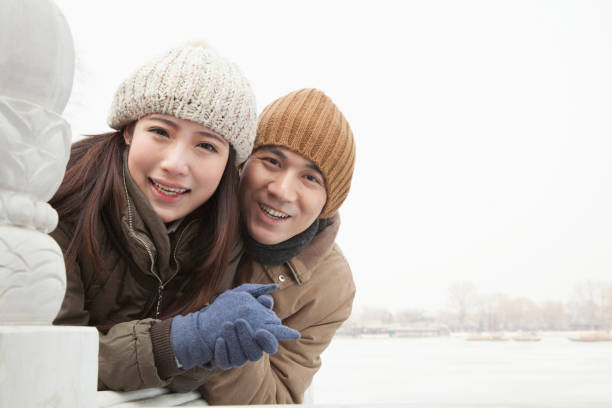 Smiling Chinese couple in gloves and caps