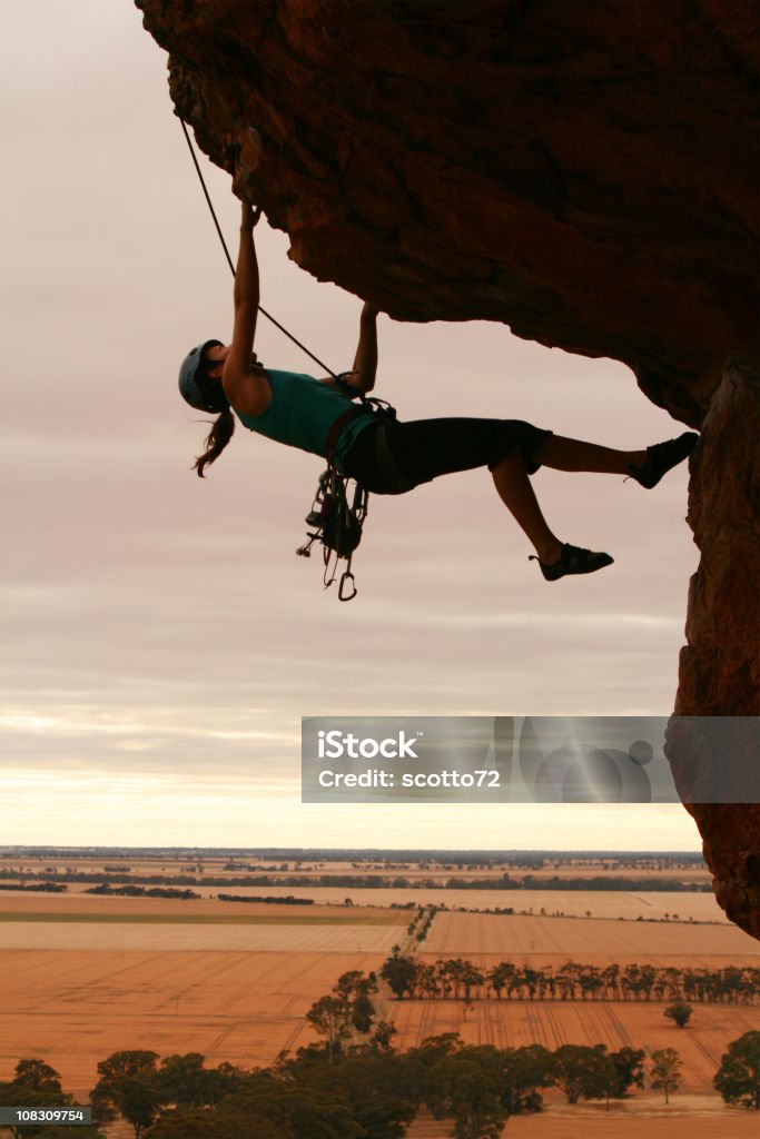 Kobieta rockclimbing sylwetka - Zbiór zdjęć royalty-free (Nawis skalny)