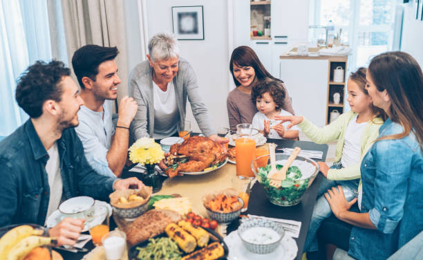 Senior woman serving roasted turkey Senior woman serving roasted turkey to big family big family table stock pictures, royalty-free photos & images