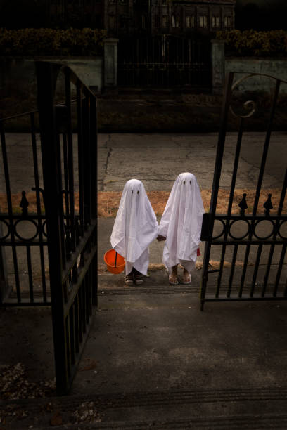 Children Trick or Treat in Ghost Costumes at Haunted House stock photo