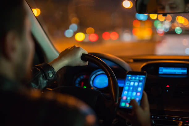 the man phone inside a modern car in the city. evening night time - car dashboard night driving imagens e fotografias de stock