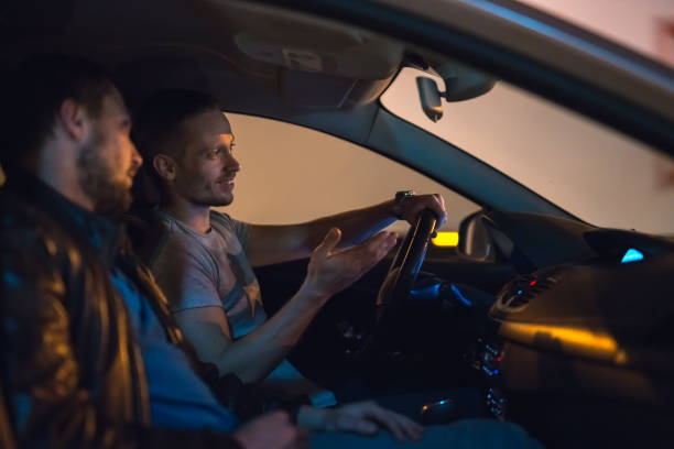 The men talk inside the car. Evening night time
