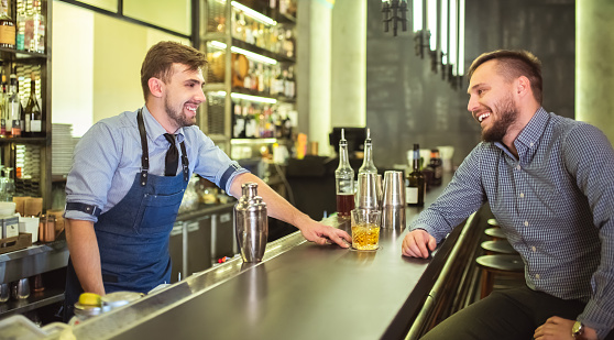 The barman talking with a visitor at the bar