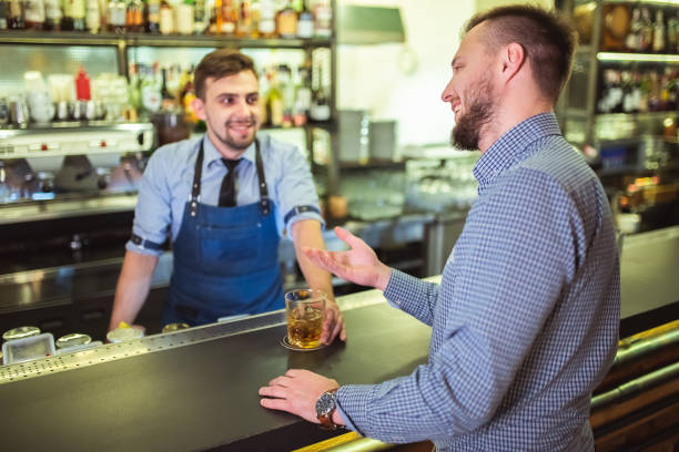 el barman feliz discutiendo con un visitante en el bar - two party system fotografías e imágenes de stock