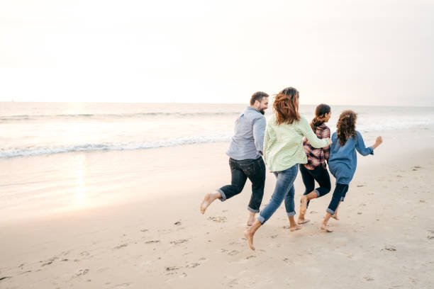 istock Two parents and two kids running on the beach 1083105940