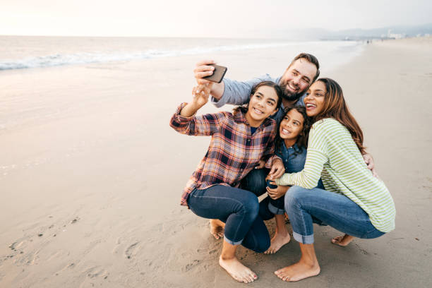 Two parents and two kids running on the beach